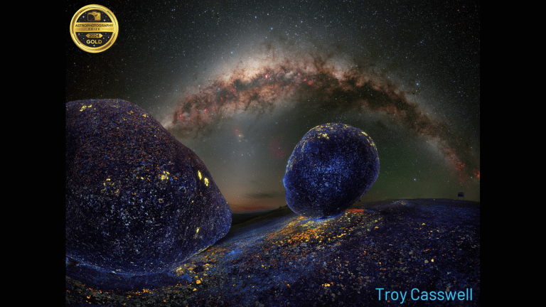 two rocks in foreground, milky way in background