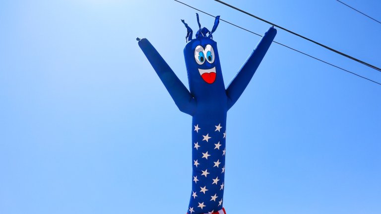 Inflatable flailing tube man balloon against blue sky